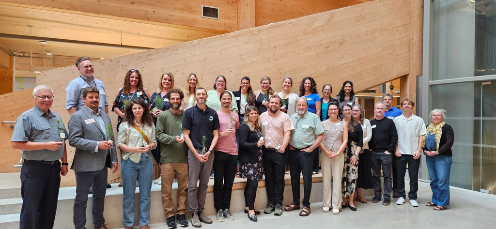 Members of the Ontario Biodiversity Council stand in the lobby of the Toronto and Regional Conservation Authority main office in September of 2025. The photo shows a few dozen people standing in a group smiling and holding tree saplings.